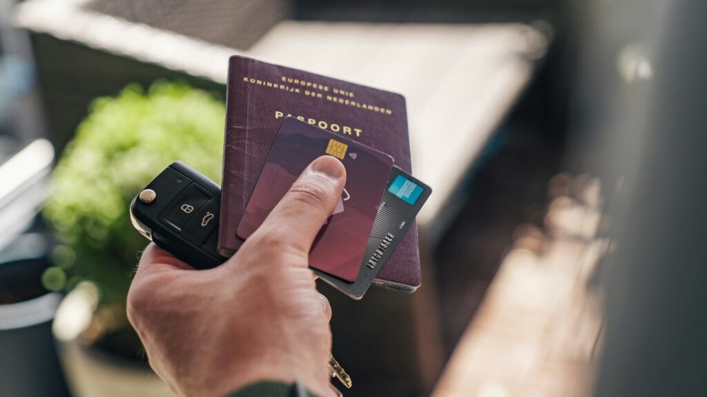 A man's hand holding a passport and car keys