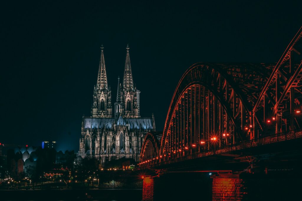 Cologne's cathedral behind a bridge lit up with festive colours